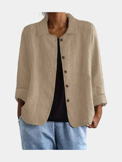 Open blouse in sand with a fine crinkle texture and two hip pockets, worn over a black top