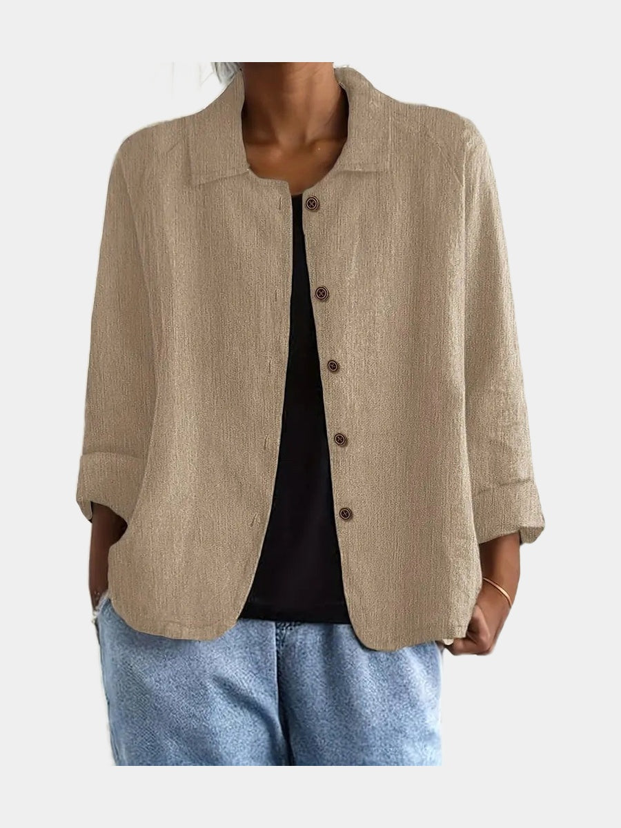 Open blouse in sand with a fine crinkle texture and two hip pockets, worn over a black top