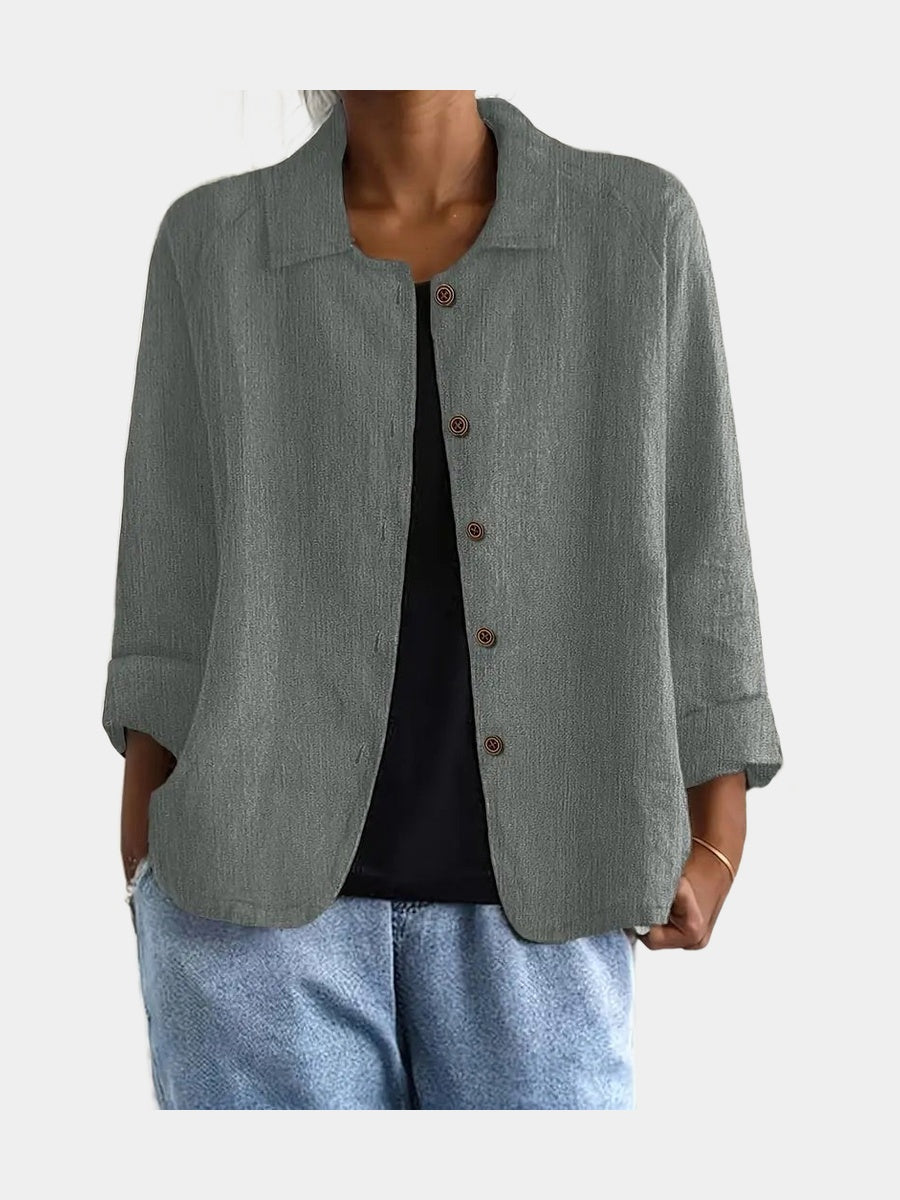 Open blouse in a green-toned grey with a crinkled weave and slanted pockets, worn over a black top