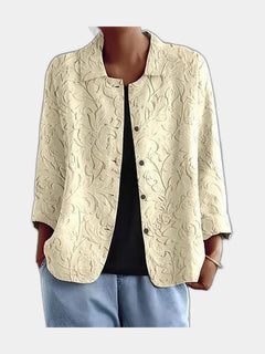 Pale open blouse with a raised tone-on-tone floral worked into the surface, worn over a black top