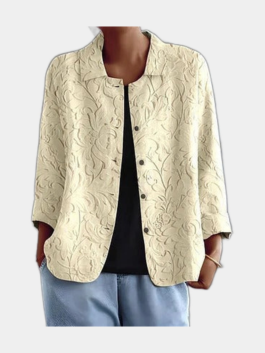 Pale open blouse with a raised tone-on-tone floral worked into the surface, worn over a black top
