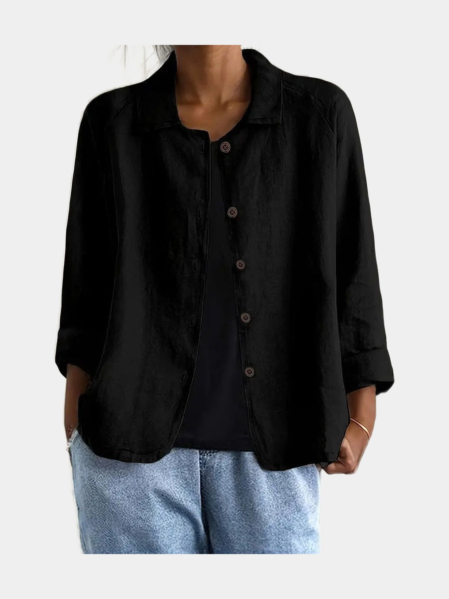 Open blouse in black with a full button front and curved hem, worn over a black top