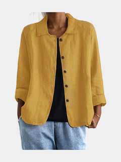Open blouse in warm ochre with a lightly slubbed surface, worn over a black top