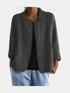Open blouse in charcoal with fine vertical crinkle texture and slanted hip pockets, worn over a black top
